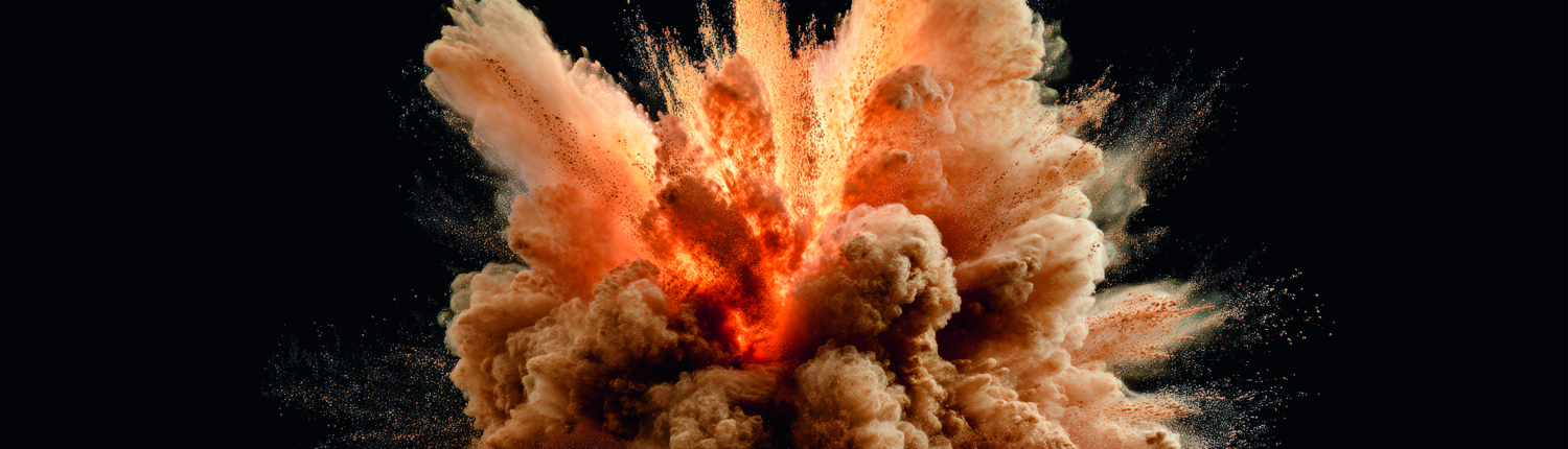 Explosive cloud of vibrant orange dust on black backdrop.